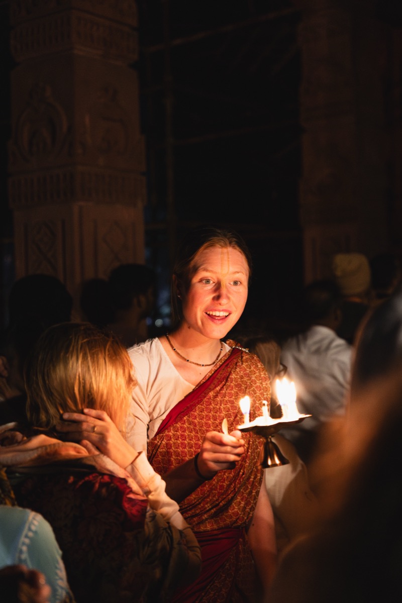 A devotee joyfully offering an arati lamp during temple worship